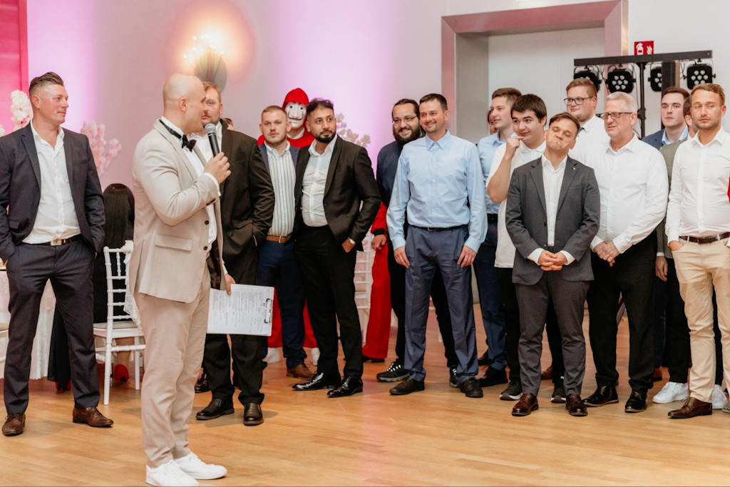 Hochzeitsmoderator mit Mikrofon und eine Gruppe G&auml;ste w&auml;hrend der Feier